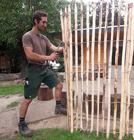 Simon baut an einem Zaun aus Holz